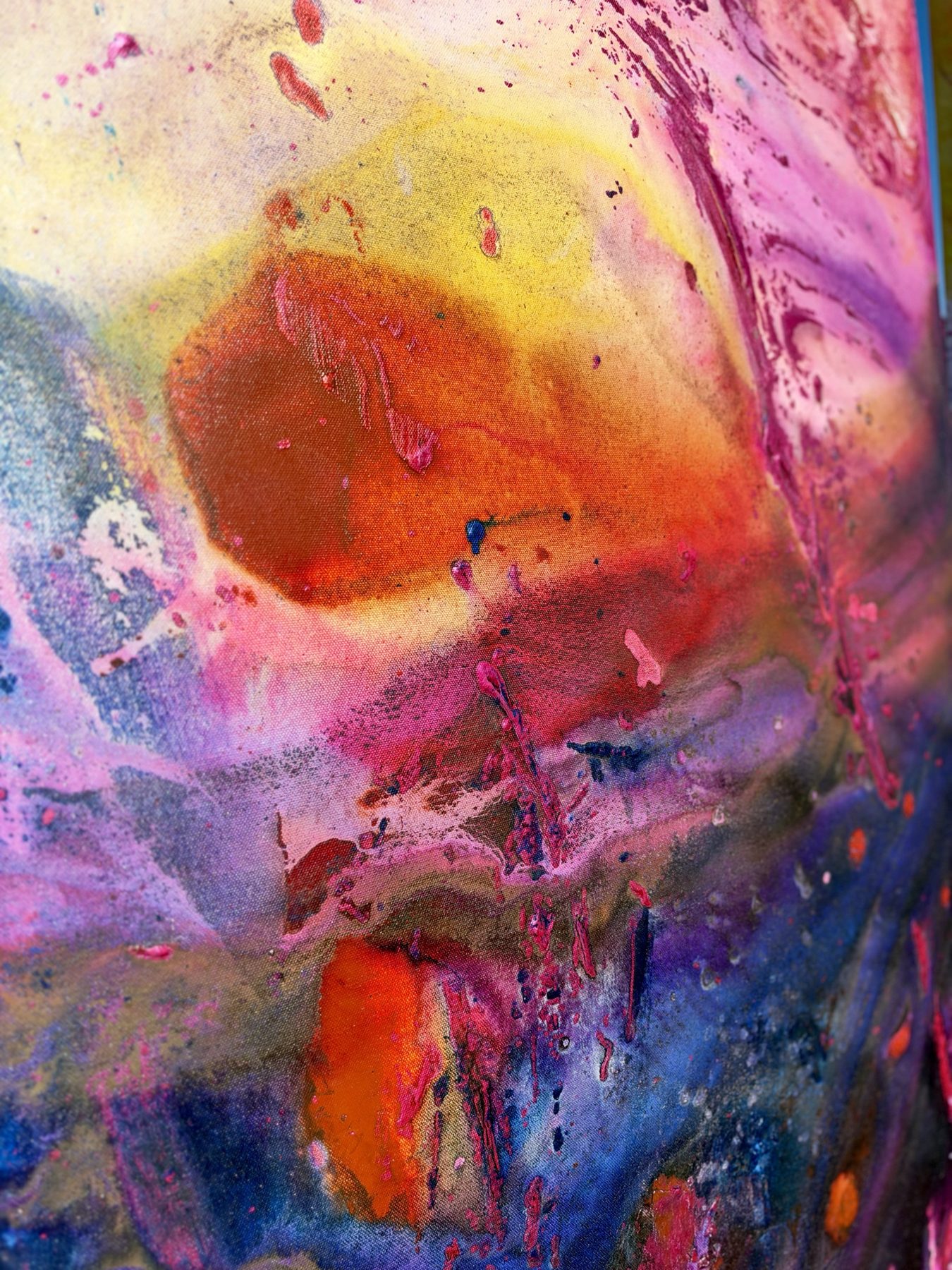 Close detail of an orange and rust pool inside a yellow and pink wash, with blue below.