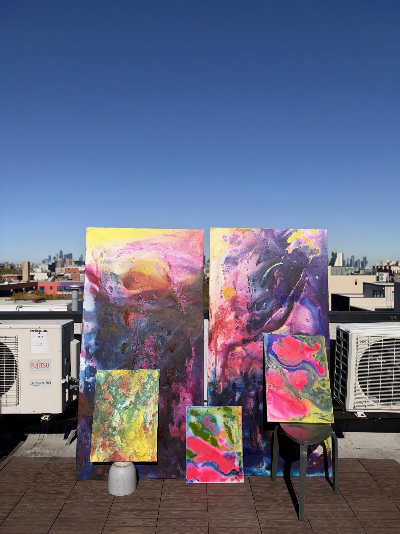 The two large paintings with three smaller pink, green and yellow canvases propped in front of them.