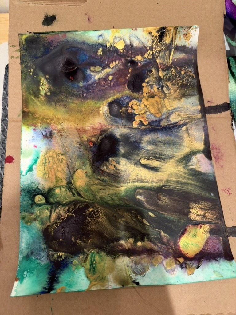 A second paper test on cardboard, teal and black pours with gold.